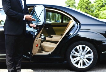 Private chauffeur opening the rear door of the car